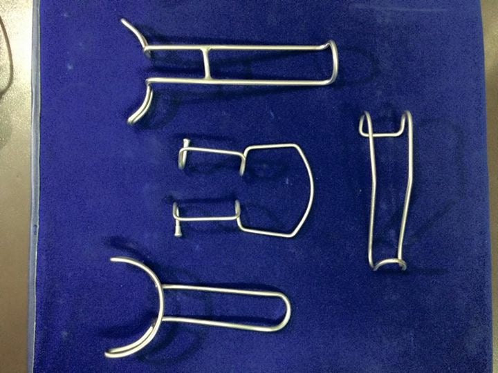 Metal dental Oringer Cheek Retractors tools on a blue background